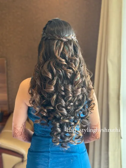 Extremely voluminous and defined curls in a half-up style with a braided accent. This is a statement look for someone who loves big, beautiful hair.