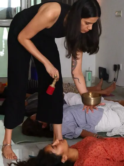 Akanksha uses a singing bowl to help ground the energy in the room during a breathwork session, combining sound and breath for a deeply immersive healing experience.
