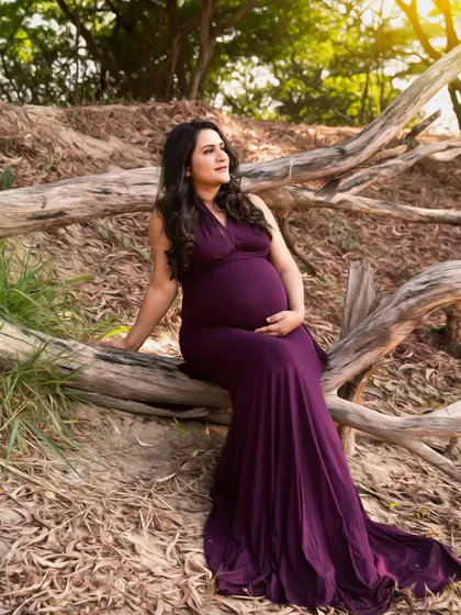 A wider shot of the mother-to-be seated on the log, showcasing the beautiful texture of the woods and the elegance of her pose.