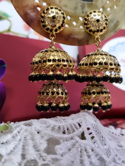 The "Kajal" Jhumkas are a statement piece, featuring black beads and intricate gold-plated latticework. This image showcases their double-layered design, perfect for a bold, traditional look.