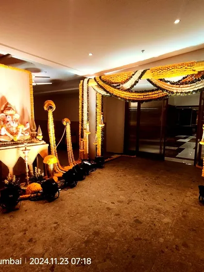 An entrance for a wedding ceremony featuring a Ganesha idol and traditional marigold floral decor. The setup includes long marigold garlands and spotlights to create a warm, inviting, and auspicious welcome.