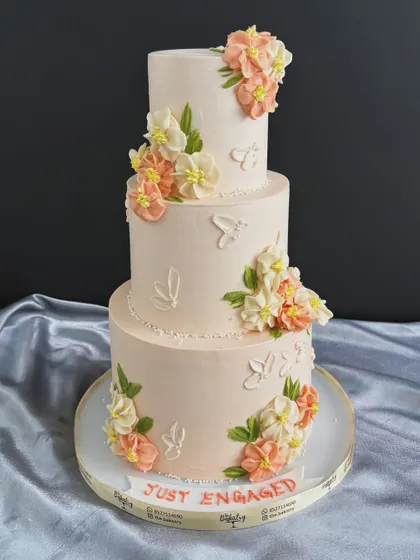A full view of the elegant "Just Engaged" cake, adorned with cascading sugar flowers and subtle butterfly imprints.
