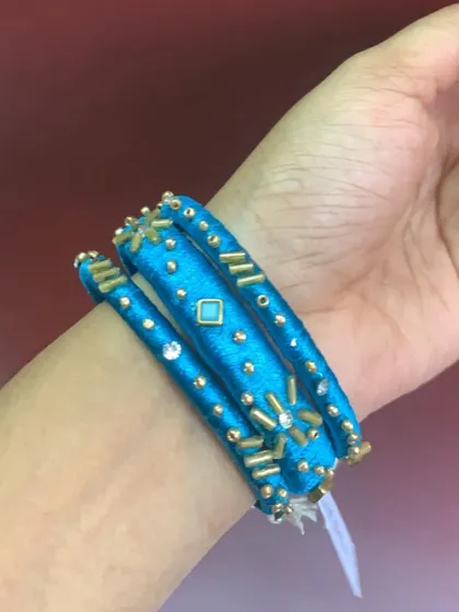 A fun and unique set of blue silk thread bangles with varied designs, including beadwork and star charms.