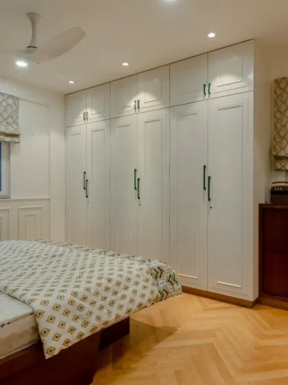 The herringbone pattern of the wooden floor, the diamond pattern of the roman blinds, and the clean lines of the wardrobe all work together to create a richly textured bedroom.