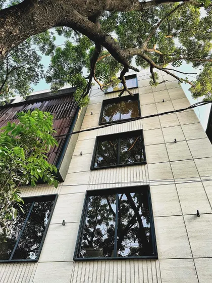 This shot captures the clean vertical lines of the mixed-use building, contrasting the smooth facade with the organic forms of the adjacent tree.