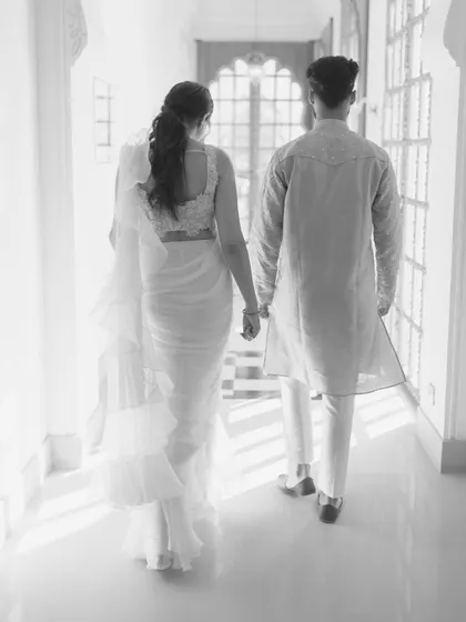 A black and white shot of Sandy and Darsh walking away, hand in hand, down a light-filled corridor. It's a quiet, narrative moment that speaks of their journey together.