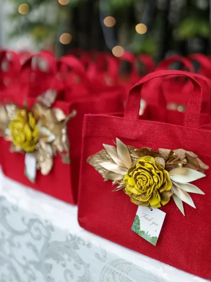 Thoughtful guest favors in bright red jute bags, each adorned with a beautiful handcrafted flower and a thank you tag.