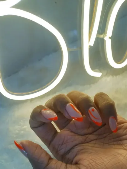 A close-up of the neon orange abstract nails against our studio's neon sign. So cool.