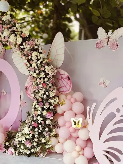 Another beautiful butterfly-themed setup, this one features a large floral and balloon backdrop. The mix of textures and colors creates a rich and visually interesting stage.