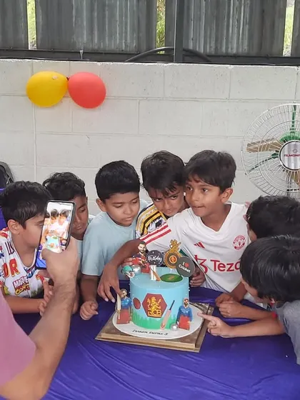 The birthday boy and his friends gathered around an awesome custom cake after a high-energy cricket and football party.