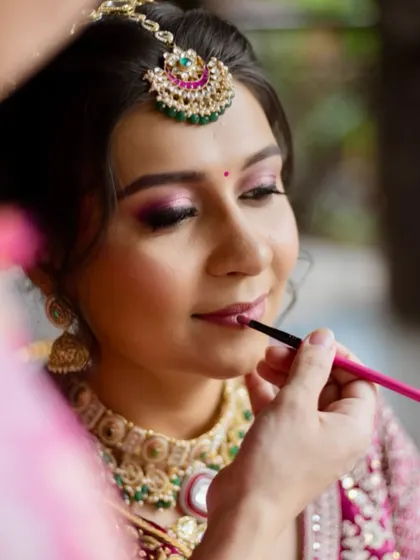 A behind-the-scenes moment of applying the final touches. This shot shows the detail that goes into creating the perfect bridal lip to complement the soft pink eyeshadow and flushed cheeks.