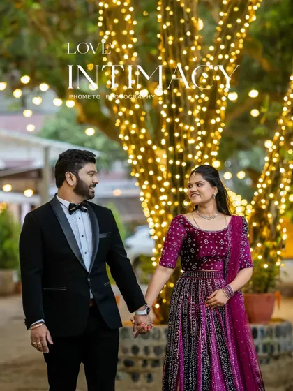 'Love & Intimacy'. The couple walks hand-in-hand under trees wrapped in fairy lights, creating a magical and romantic atmosphere.