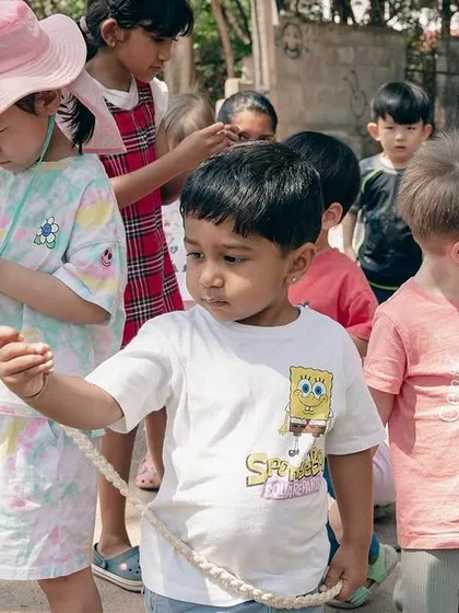 Our students hold a walking rope during a trip to the nursery, their faces full of curiosity.