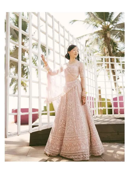 An elegant portrait of the bride in her beautiful pink lehenga. The natural light and coastal backdrop create a fresh and modern bridal shot.