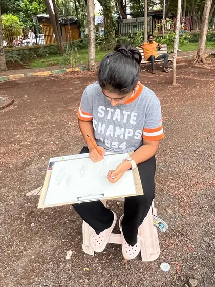 Another student deeply focused on her clipboard, sketching the scenes around her. Outdoor drawing is a practical application of the anatomy and perspective lessons learned in the studio.