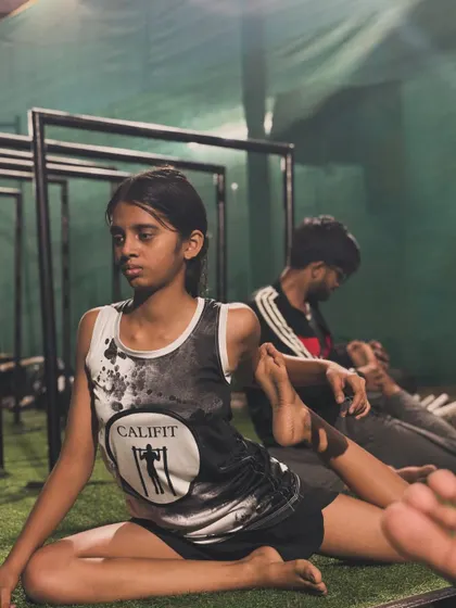 A young girl working on her hip flexibility. Her focus is incredible.