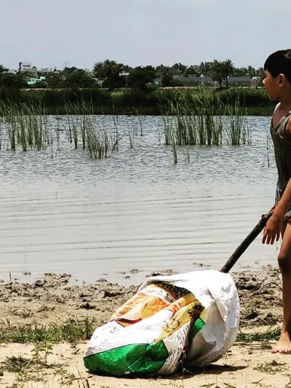 A child single-handedly transports a heavy bag of harvested clay. This moment shows incredible determination and the development of practical problem-solving skills, using a simple stick as a lever to move the load.