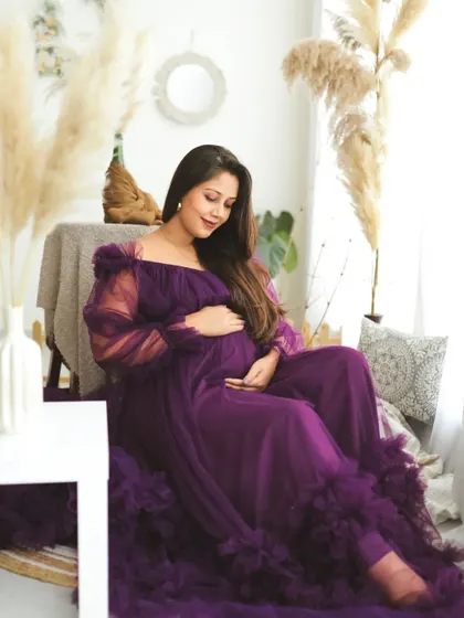 A peaceful moment captured in my lifestyle studio. The mom-to-be, dressed in a rich purple gown, looks down at her bump with love and tenderness.
