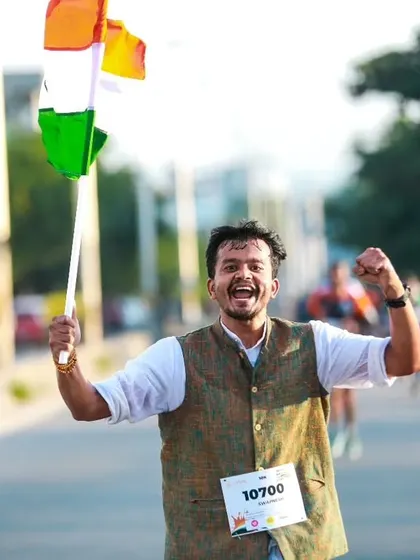 Pure joy and celebration at the finish line. A participant waves the Indian flag, celebrating both his run and the spirit of Independence Day.