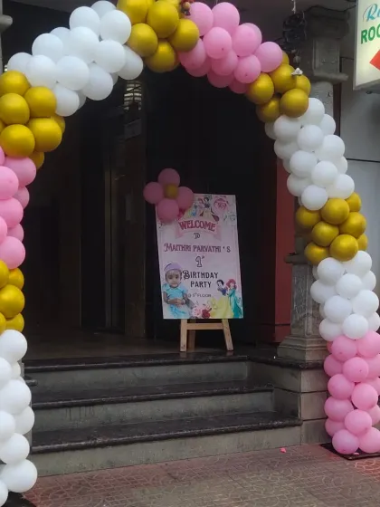 The entrance to the princess-themed party, featuring a pink, gold, and white balloon arch and a welcome easel.