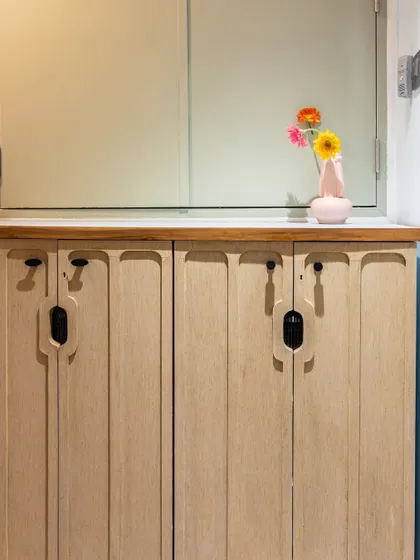 A detail shot of the custom shoe storage cabinet, featuring unique grooved handles that add an organic and modern touch to the entryway.