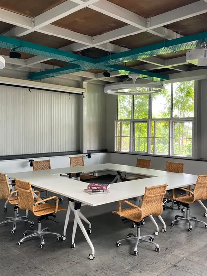 The conference room in our own MTA studio features a U-shaped table to facilitate discussion. The exposed ceiling grid, custom ring lights, and woven-back chairs reflect our industrial yet refined design aesthetic.