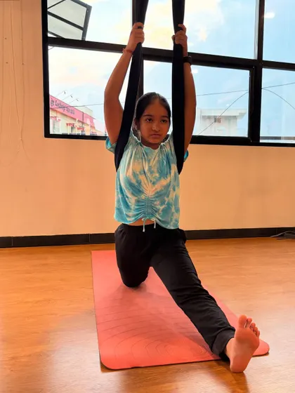 Another one of our dedicated students using the aerial silk to assist with a standing split, improving her balance and hamstring flexibility.
