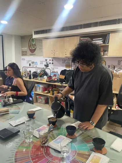 A student carefully pours water for a cupping session, ensuring consistency across all samples. Precision is key in sensory evaluation.