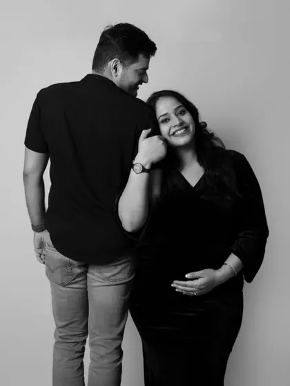 The pure joy of pregnancy shines in this black and white photo. The mother-to-be leans on her partner with a happy smile, a simple and beautiful moment.