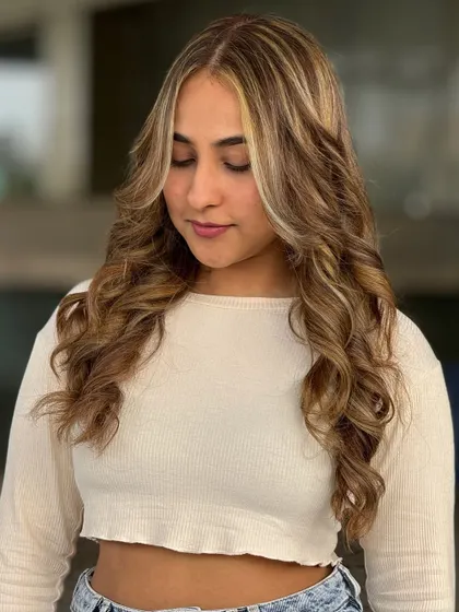 Here is another fantastic makeover by a student. This style features prominent face framing highlights, also known as a money piece, combined with soft waves for a trendy and glamorous result.