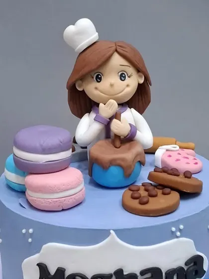 A closer look at the baker figurine, surrounded by fondant macarons and cookies.