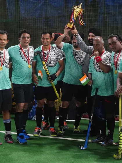 A veteran's team celebrates their tournament victory, holding their trophy and medals. The passion for hockey has no age limit in our family.