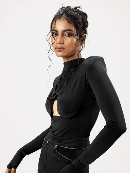 A close-up of the edgy updo with face-framing tendrils. The look is paired with a smokey eye and a lip piercing, creating a bold, modern aesthetic for the fashion campaign.