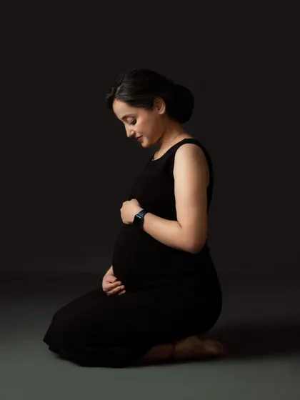 A simple, elegant, and moody solo portrait. The mom-to-be kneels, creating a powerful silhouette that focuses on her and her baby bump.
