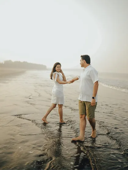 A gentle walk along the water's edge. This candid pre-wedding photograph captures a natural, comfortable moment between the couple during their beach session.