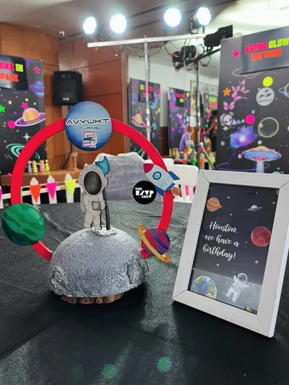 A stellar centerpiece for a space-themed party, featuring a mini astronaut on the moon, surrounded by planets. The framed sign cleverly says, "Houston, we have a birthday!"