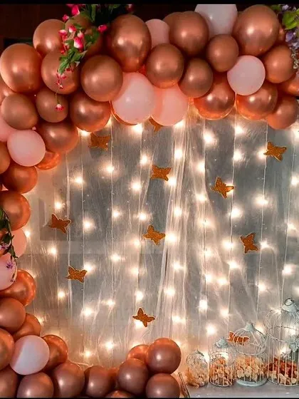 A beautiful ring backdrop featuring rose gold and pink balloons, with a curtain of fairy lights. This setup is perfect for creating a magical and romantic photo corner at any birthday celebration.