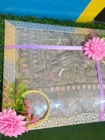 A suit packed for a Roka ceremony, decorated with purple ribbon and pink flowers.