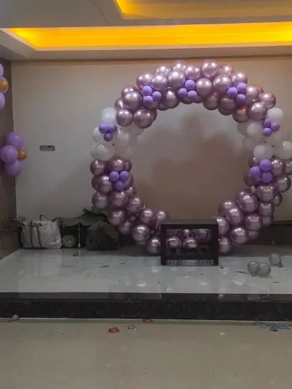 A circular balloon arch in purple and white, a versatile decor element for photo booths or stage backdrops, shown here during setup.