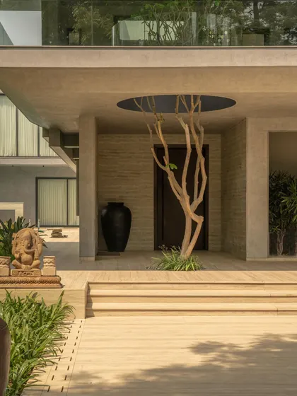 The entrance is marked by a circular void in the concrete roof, through which a tree grows. This gesture creates a powerful dialogue between the man-made structure and the natural world.