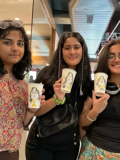A group of friends showing off their matching caricature coffee cups.