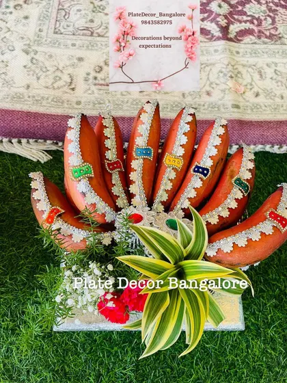 A traditional decoration for red bananas using golden fabric and multi-colored kundan stones, arranged beautifully for a ceremony.