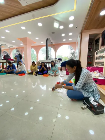 A wide shot of the flower-making session, with students learning on the floor in a traditional and relaxed setting.