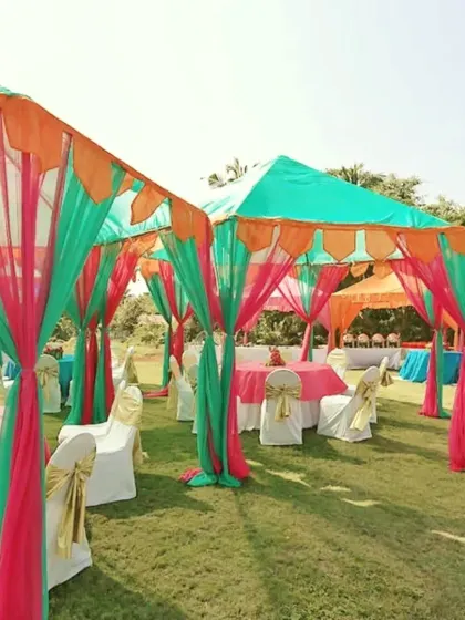 A bright and colorful tent setup for a daytime outdoor party. The canopies are decorated with green, pink, and orange drapes, and the tables are set up with matching linens.