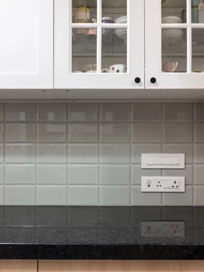 A close-up of the classic subway tiles and glass-fronted cabinets. This combination is timeless, allowing the beautiful crockery inside to become part of the kitchen's decor.