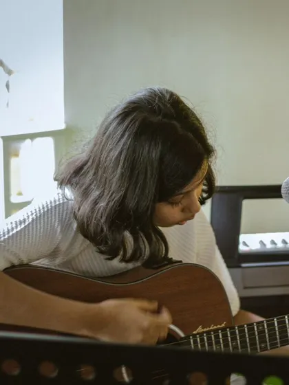 A student guitarist lost in the music during her recital performance.