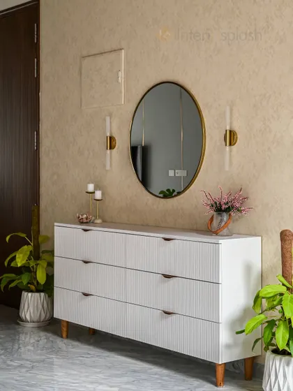 This console table setup features a fluted white cabinet, a large oval mirror, and warm wall sconces. It's a perfect example of a stylish and functional entryway or hallway accent.