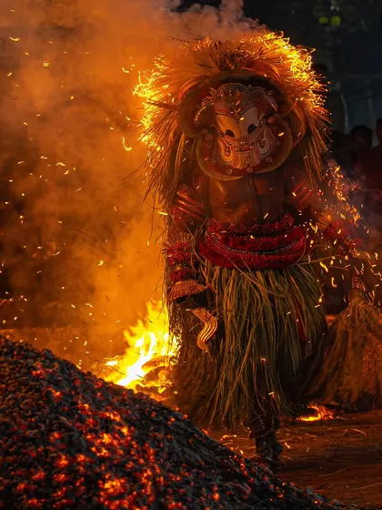 The Pottan Theyyam, an anti-caste god, walks through a bed of hot coals. This powerful image captures the essence of the ritual, which symbolizes resistance against social injustice.