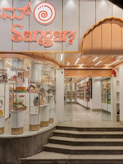 The storefront for Sangam Sweets in Bangalore, where we blended traditional Indian architectural elements with a modern retail experience. The multi-foliate arched entrance and fluted peach fascia guide customers inside. This design respects the brand's rich history while creating an inviting and contemporary street presence.