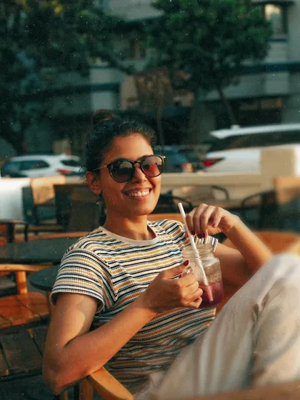 A candid, smiling shot at an outdoor cafe, capturing a genuine moment of happiness.